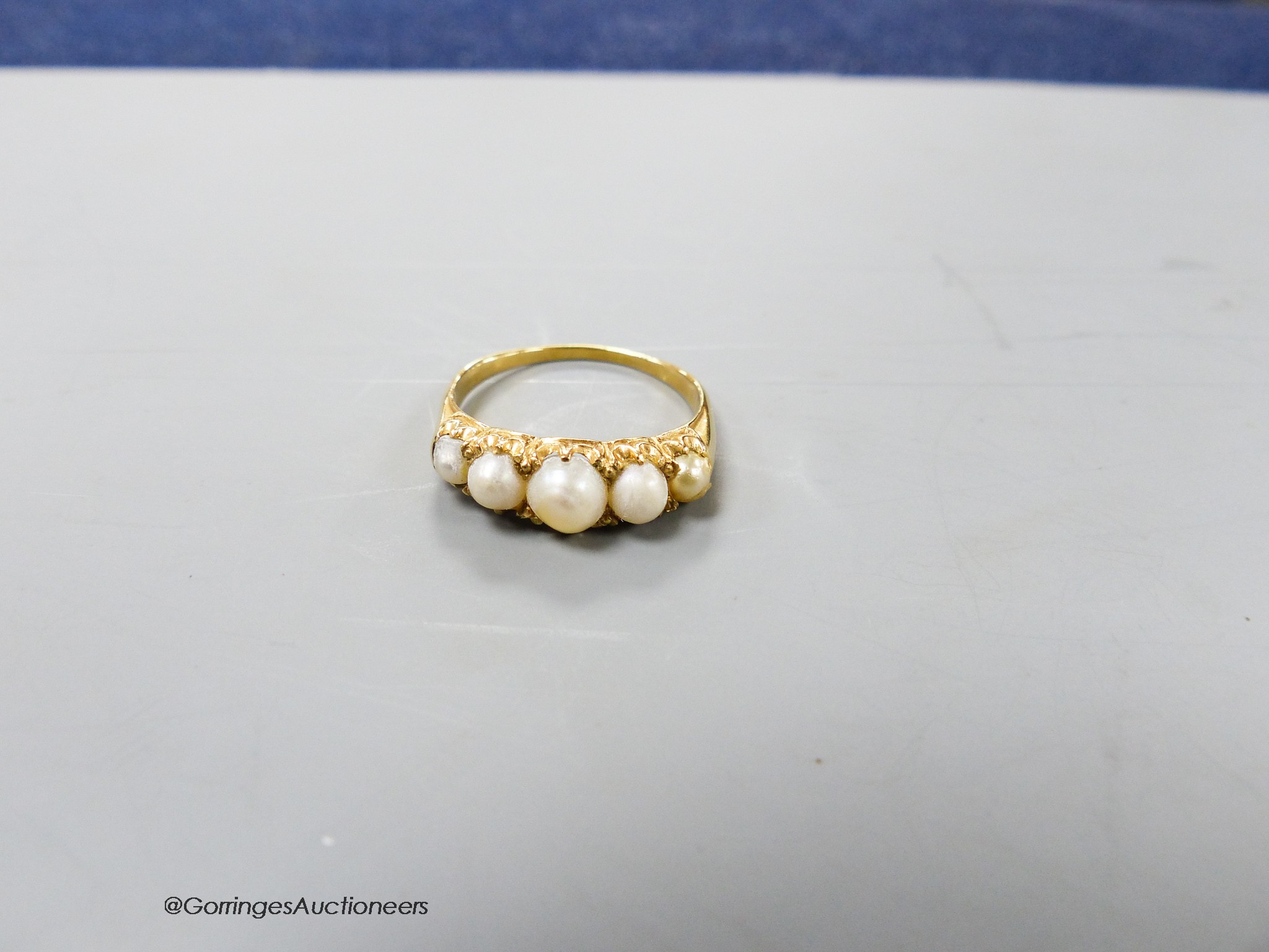 A yellow metal and graduated five stone split pearl half hoop ring, size R, gross weight 3.8 grams.